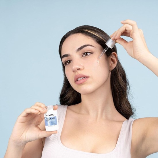 Applicazione Babaria Hyaluronic Acid Serum con Acido Ialuronico Donna che applica Babaria Hyaluronic Acid Serum con contagocce per idratazione e cura del viso.
