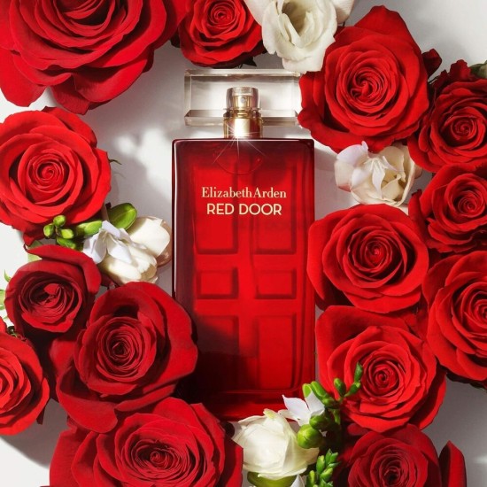 Elizabeth Arden Red Door Eau de Toilette Donna 100 ml con flacone tra rose rosse Flacone di Elizabeth Arden Red Door Eau de Toilette Donna 100 ml circondato da rose rosse e fiori bianchi, immagine promozionale del profumo.