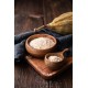 Ciotola e cucchiaio in legno contenenti polvere di baobab su tavolo in legno con frutto di baobab sullo sfondo.